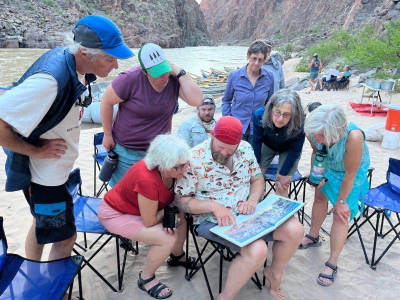 A group of people are looking at a map on the beach