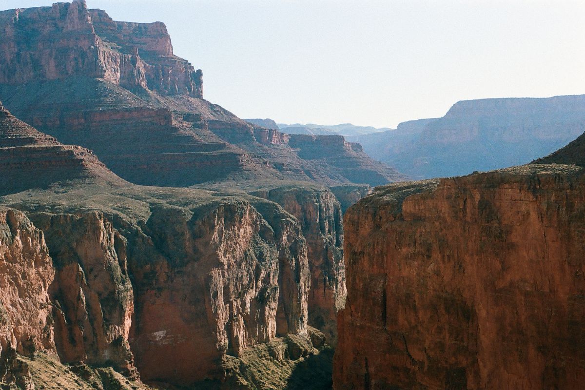 Grand Canyon vista of layered red rock cliffs and canyon walls under a clear sky.