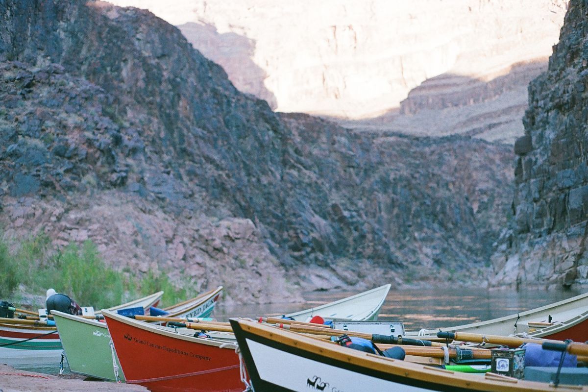 Rowboats on a riverbank with high canyon walls in the background.