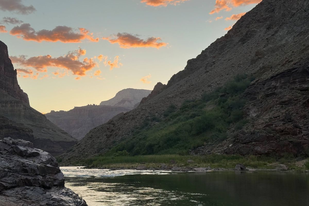 River flowing between steep canyon walls under a sunset sky.