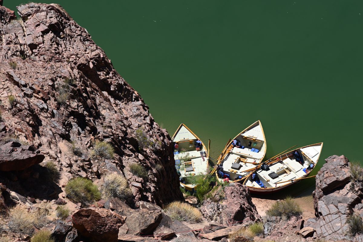 Three boats are sitting on a rock near a body of water