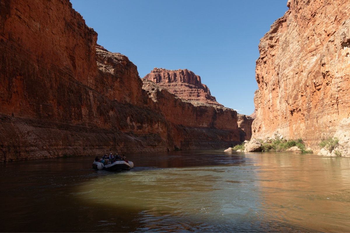 A boat is floating down a river in a canyon.