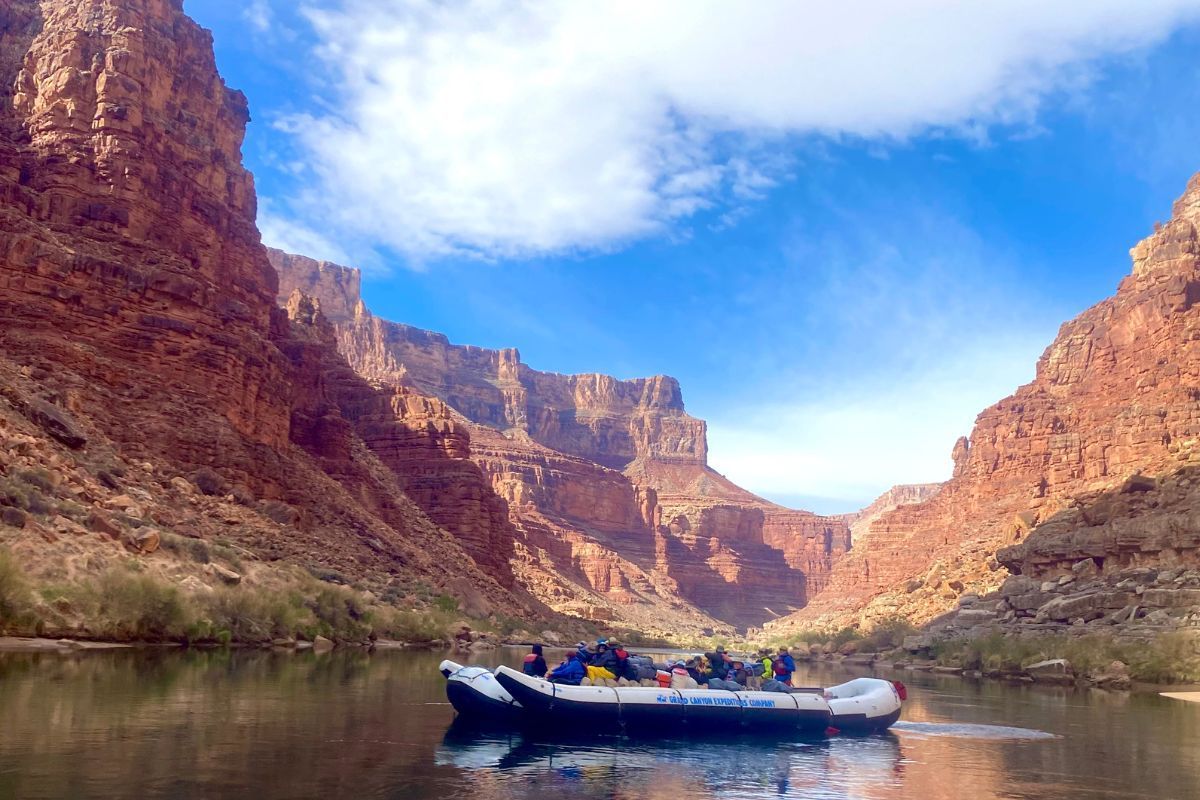 A group of people in a boat on a river with mountains in the background