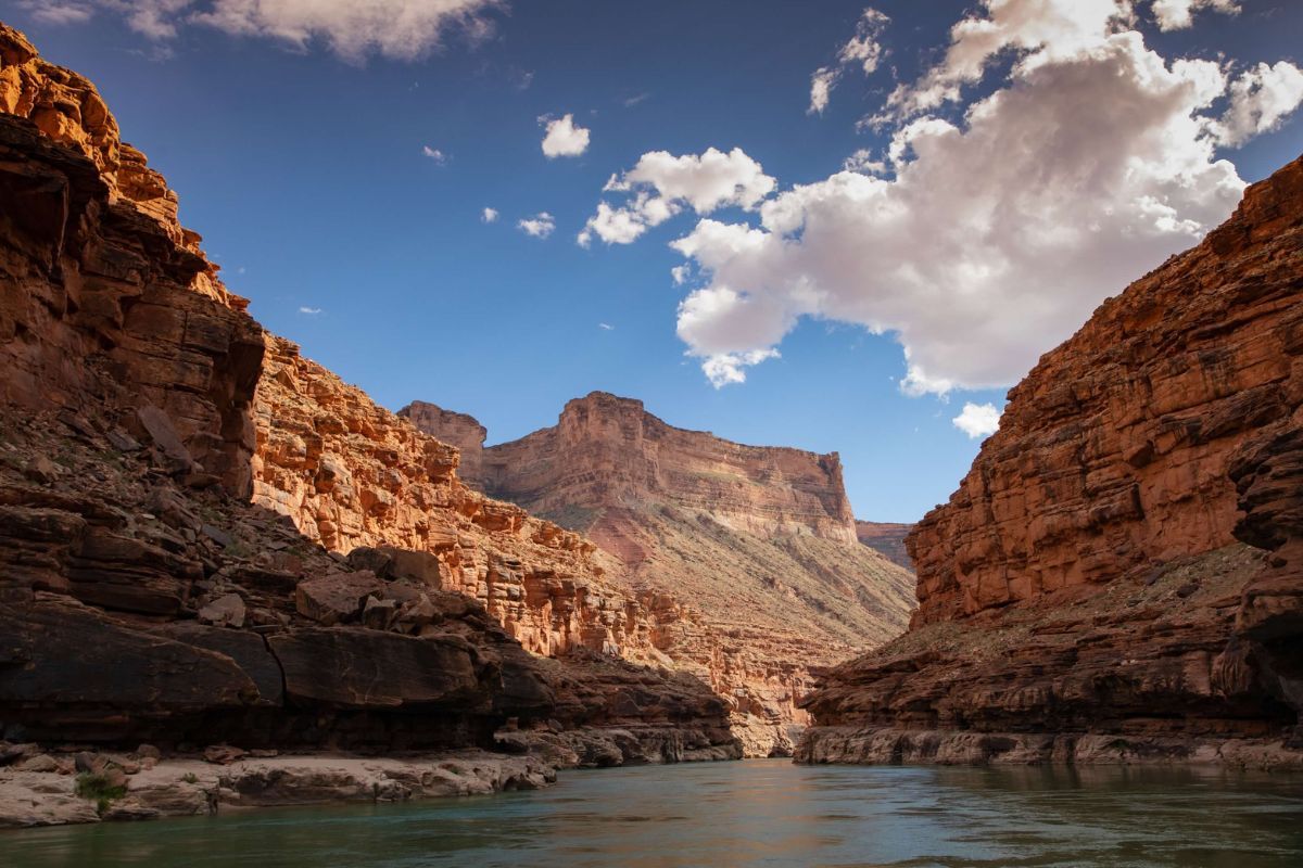 A river flowing through a canyon with mountains in the background