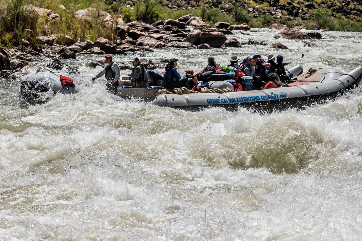 A group of people are rafting down a river in a raft that has the word raft on it