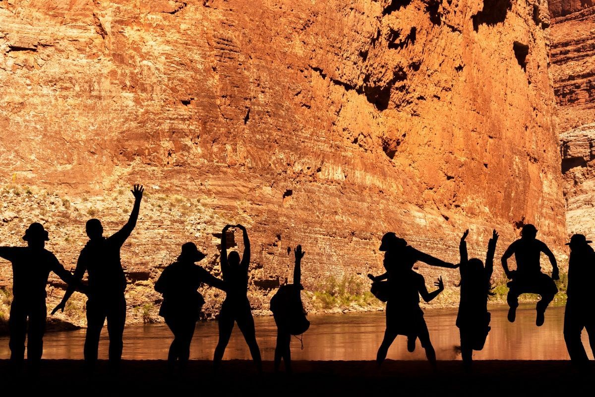 A group of people are standing in front of a rock wall