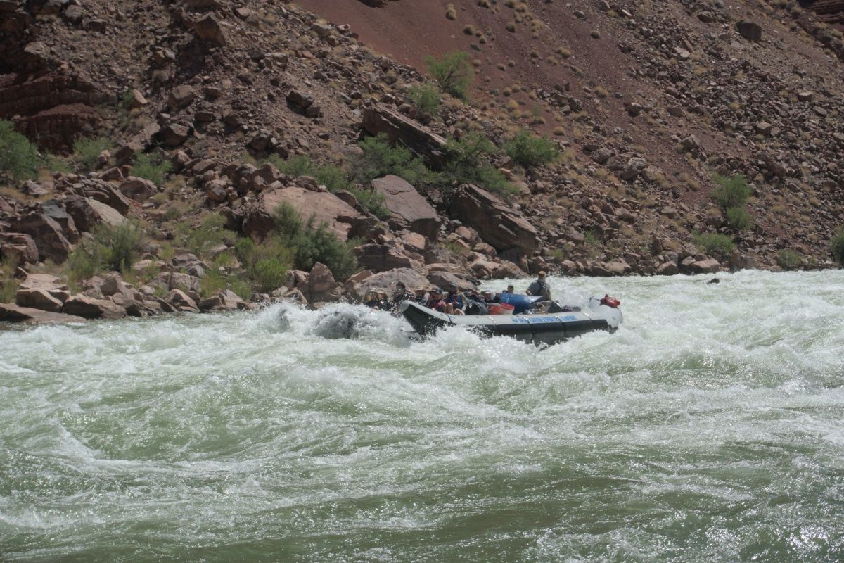 A boat is going through a rapid on a river.