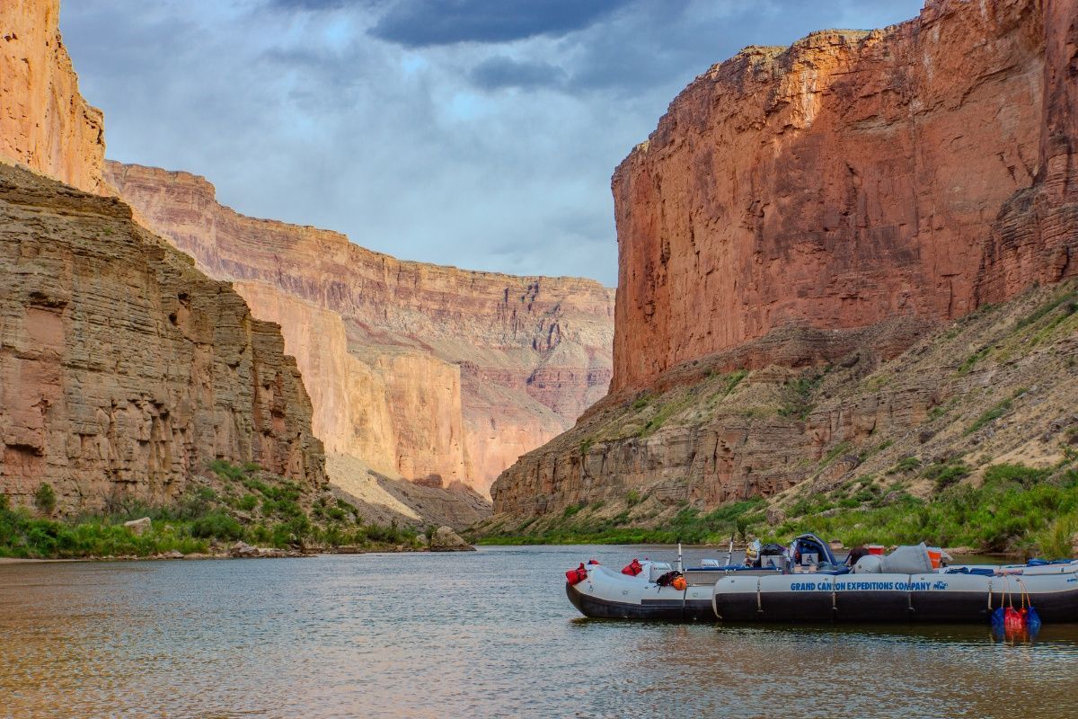 A boat is docked in the middle of a river in a canyon.