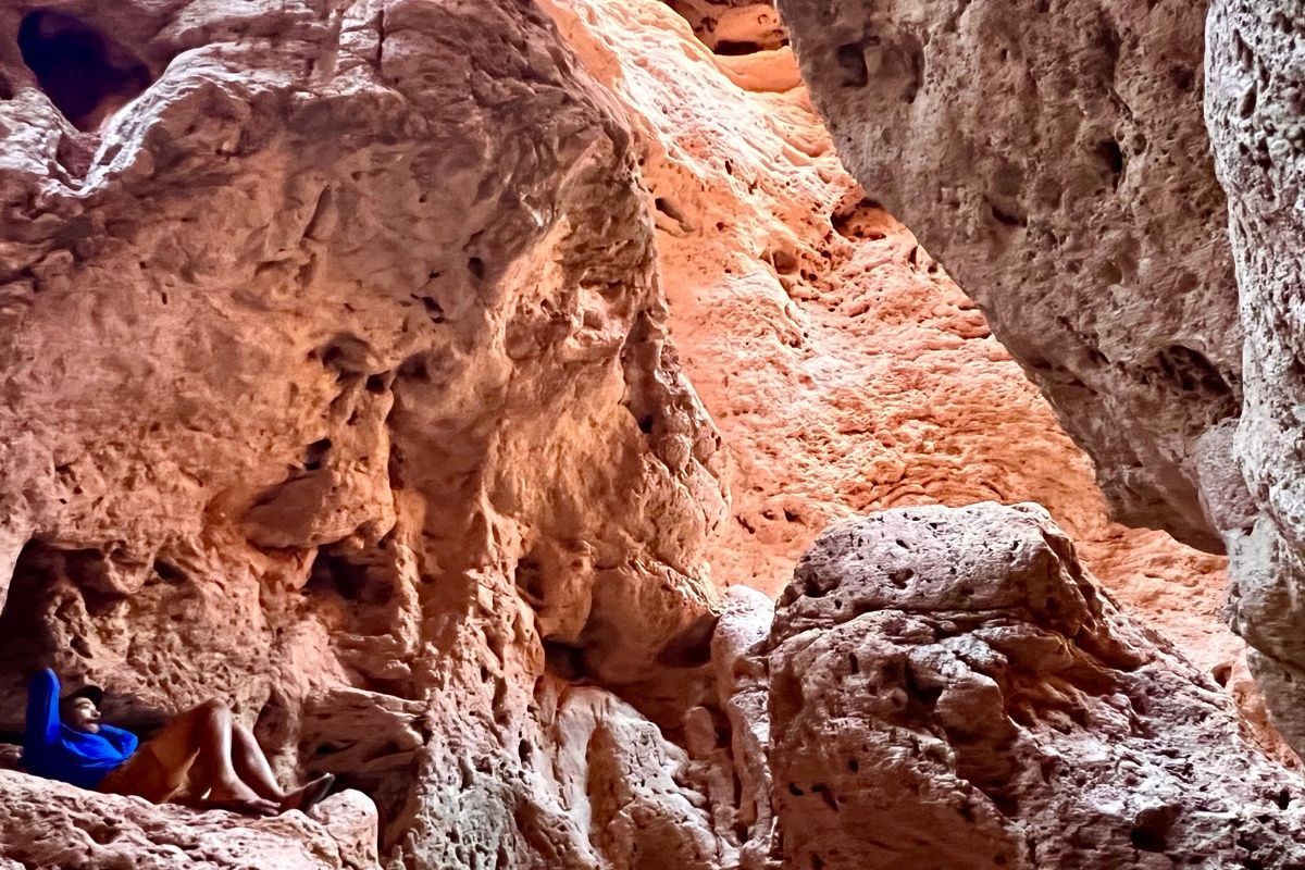 A person is sitting in a cave surrounded by rocks.