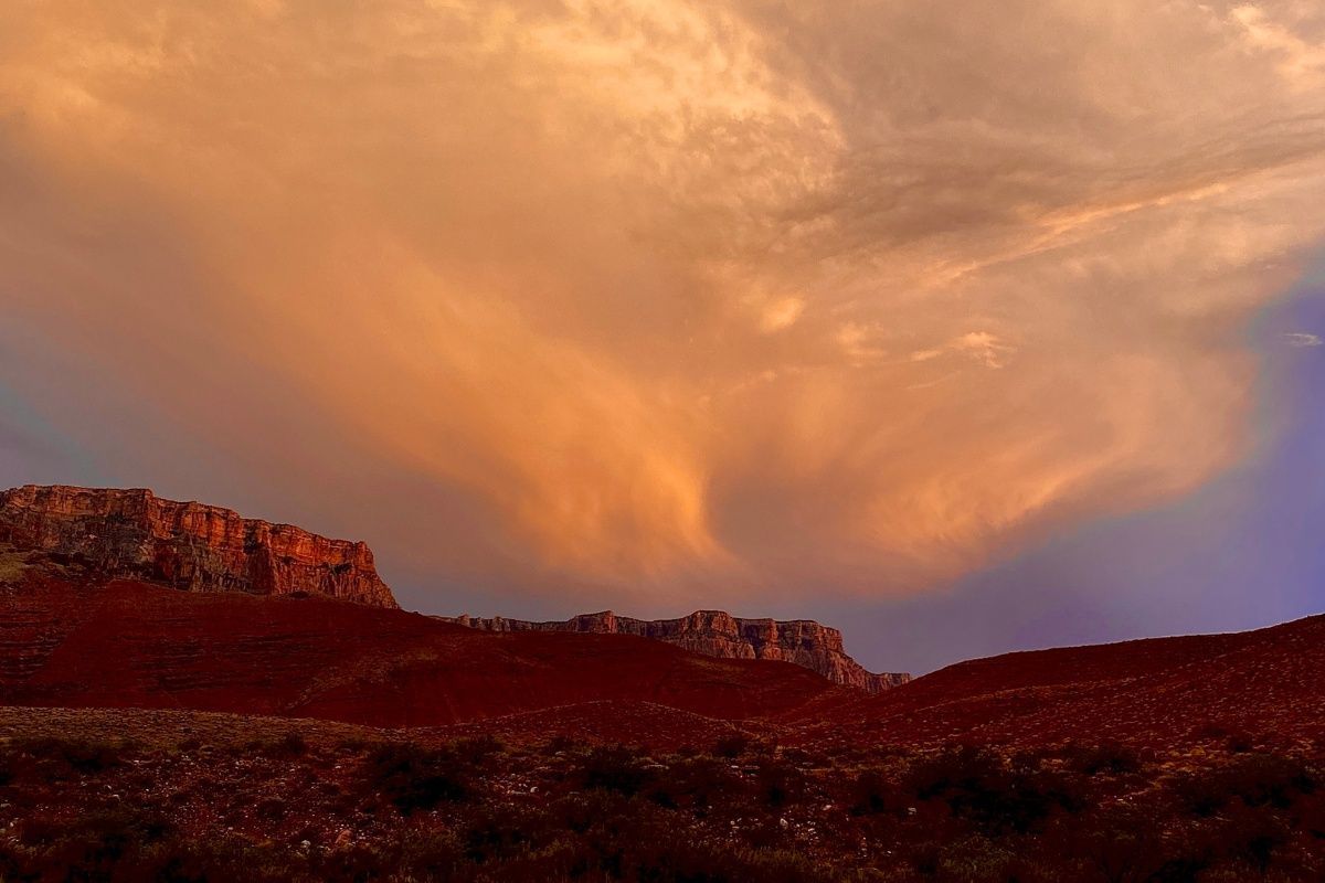 A sunset over a mountain range with a cloudy sky