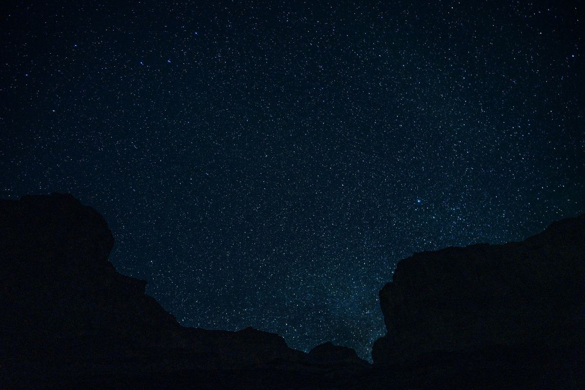 A night sky filled with lots of stars and mountains in the foreground.