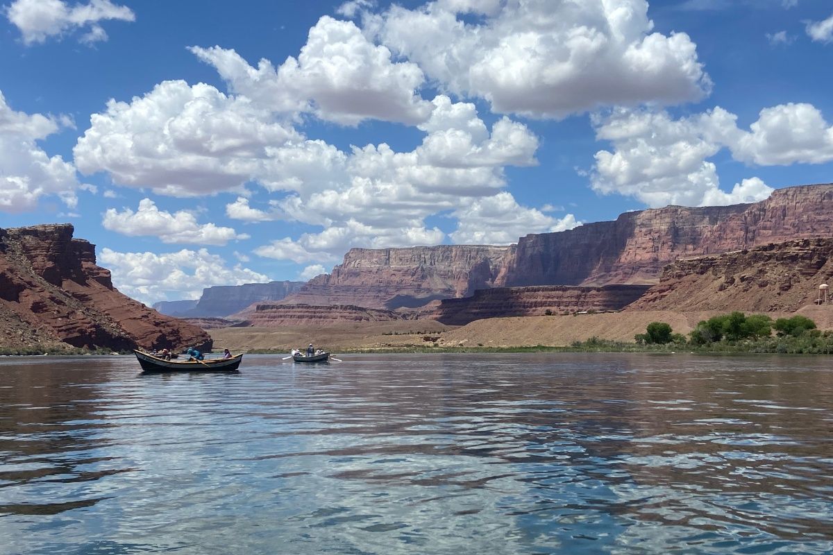 A boat is floating on a river with mountains in the background.