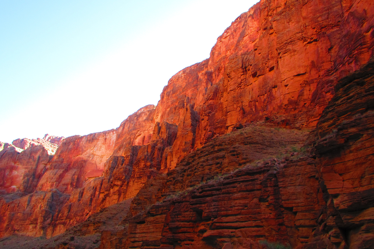 A red rocky cliff with a blue sky in the background