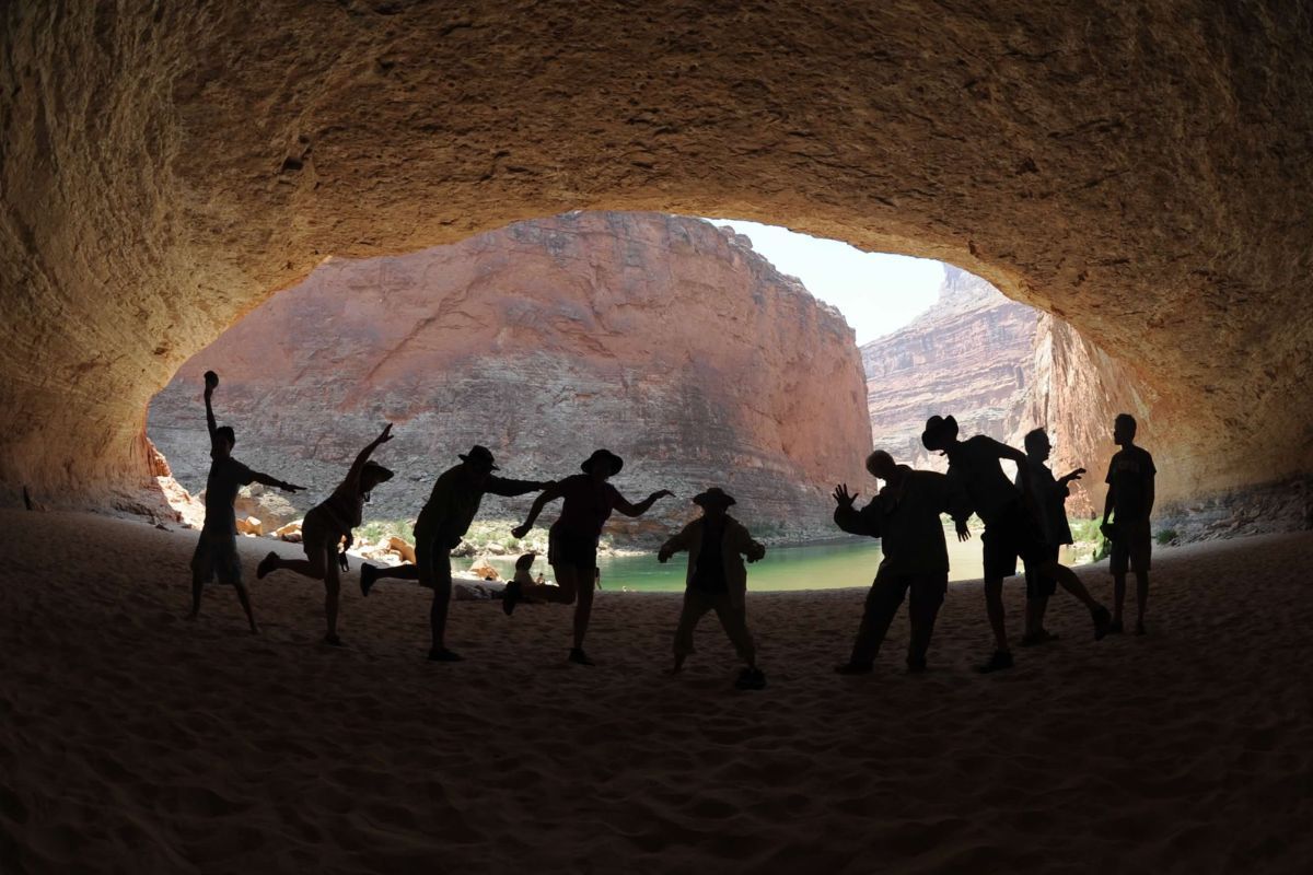 A group of people standing in a cave with mountains in the background