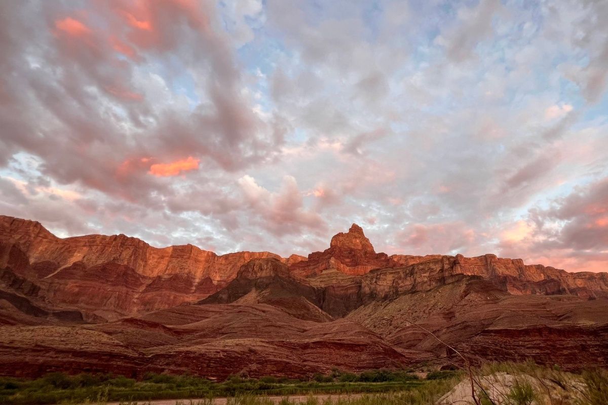 A sunset over a mountain range with a river in the foreground.