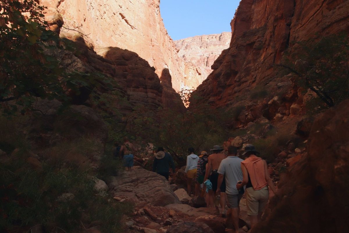 A group of people are walking through a canyon.