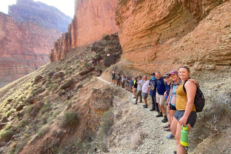 A group of people are standing on a trail in the mountains.