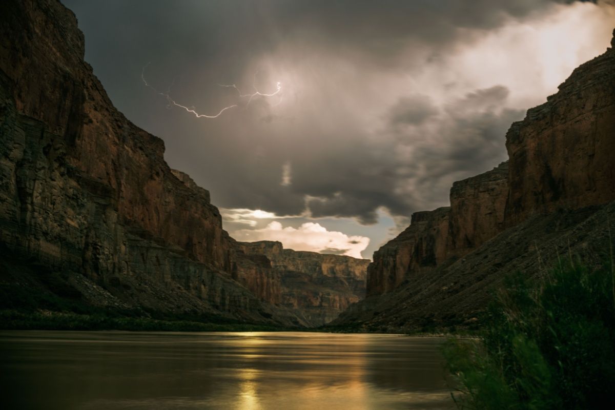 A lightning strike over a river in a canyon.