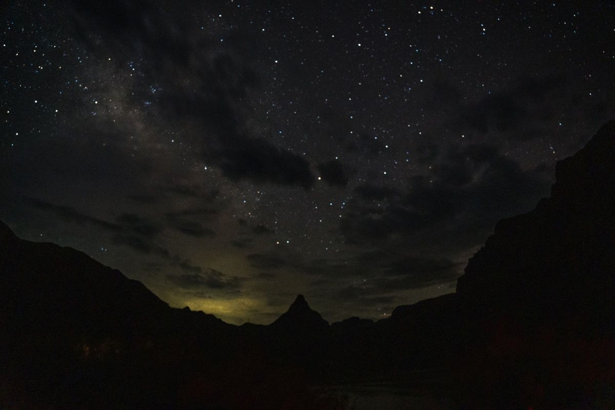 A night sky filled with lots of stars over a mountain range.