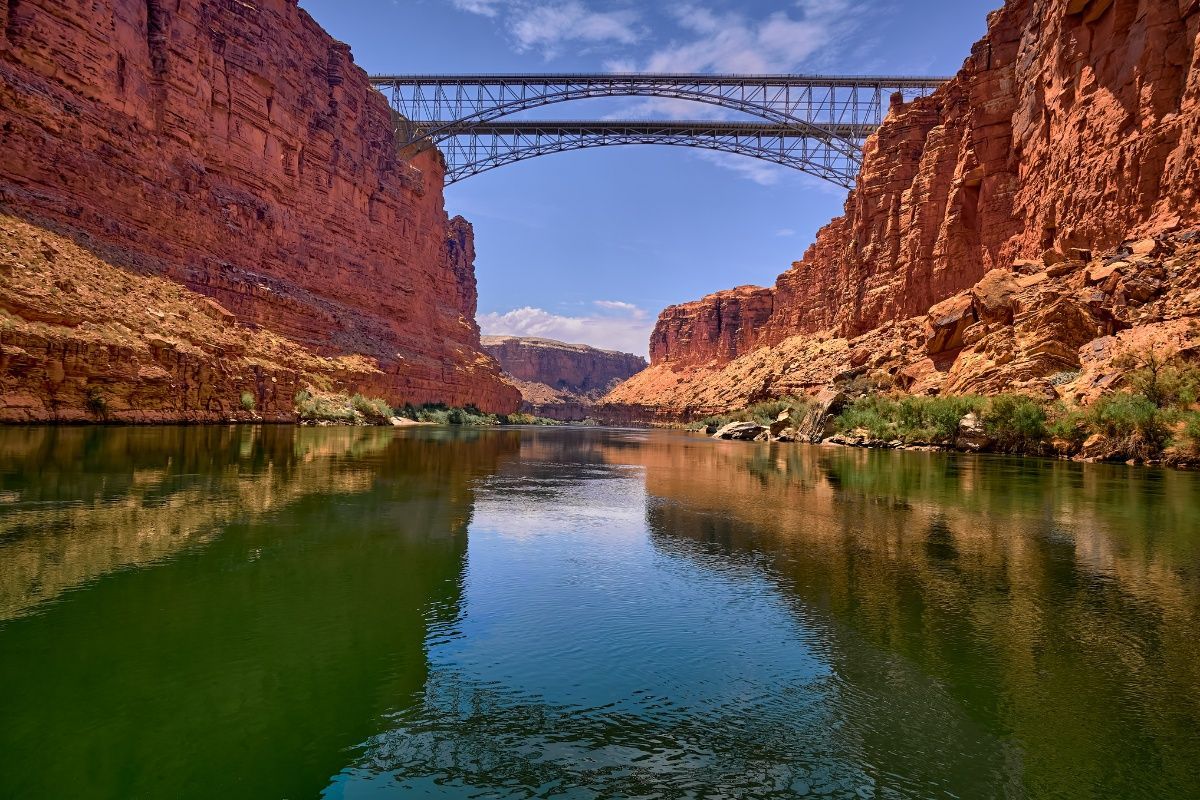 A bridge over a river in the middle of a canyon.