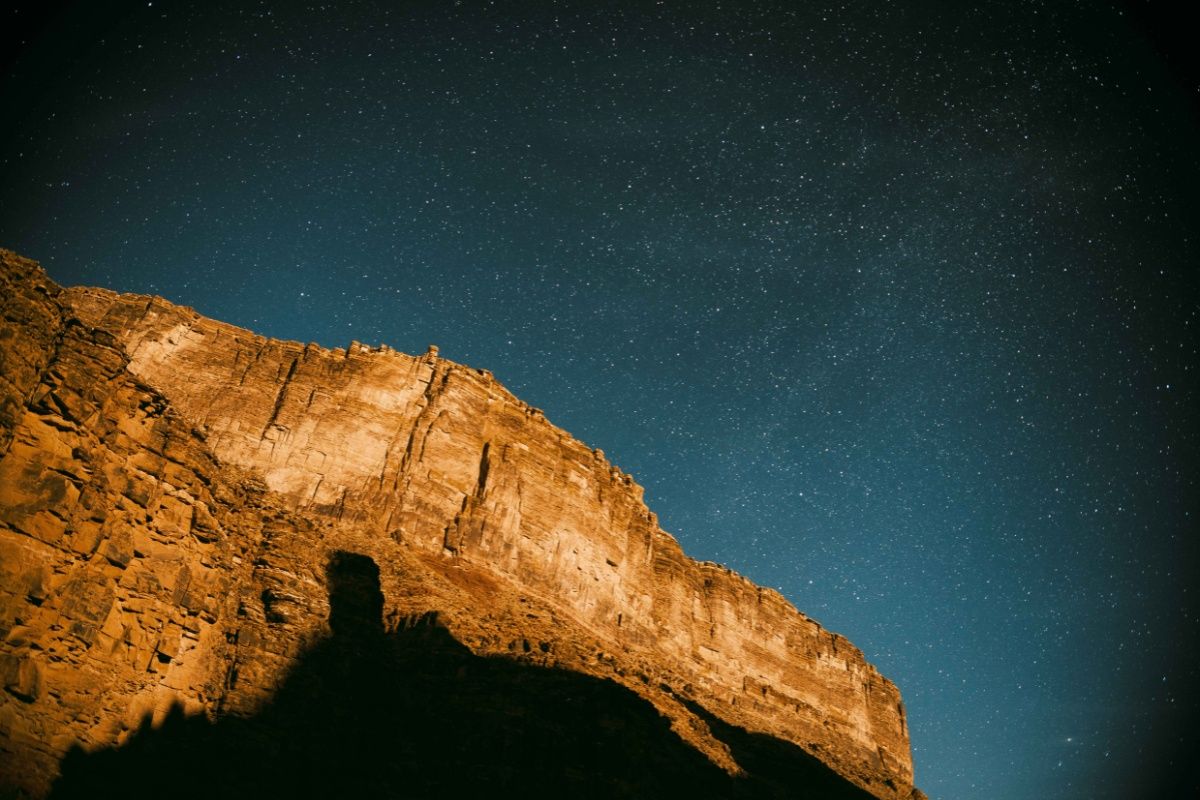 A mountain silhouetted against a starry night sky.