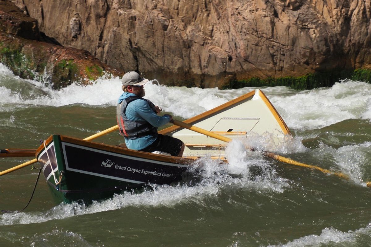 A man is rowing a boat down a river