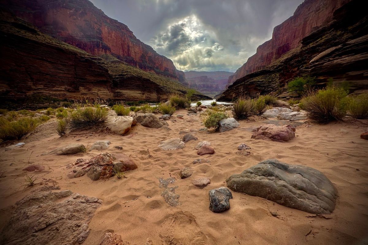 A canyon with a river running through it and rocks in the foreground.
