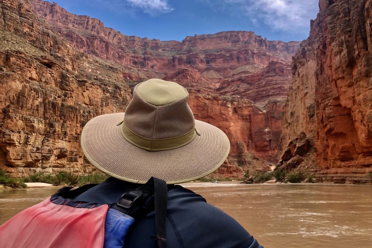 A person wearing a hat is looking out over a river