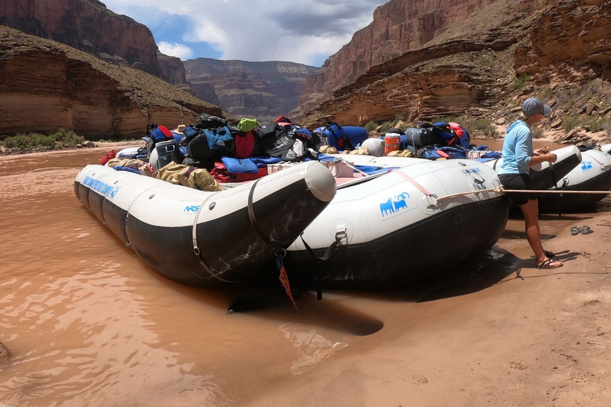A man sits on a bench next to a raft that has the word raft on it