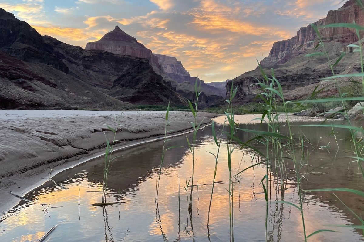 A river with mountains in the background and a reflection of mountains in the water.