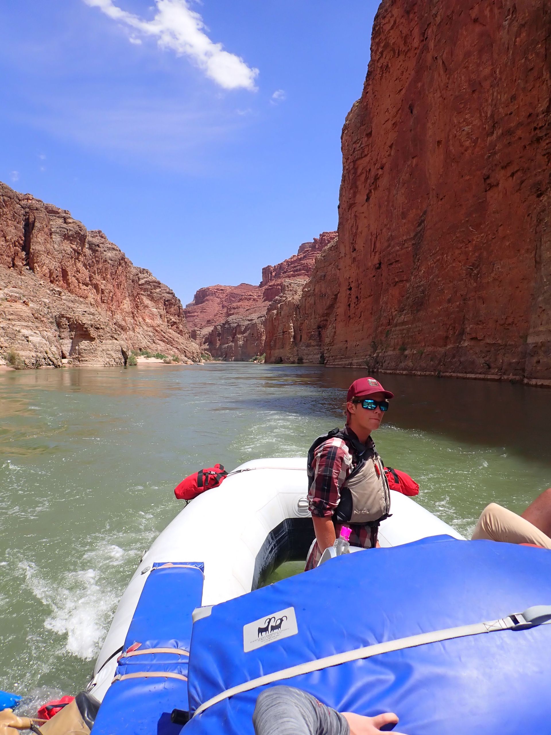 A man in a red hat is in a boat on a river