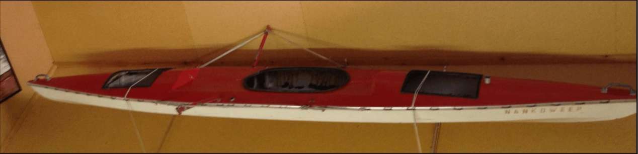 A red and white boat is hanging on a wall.