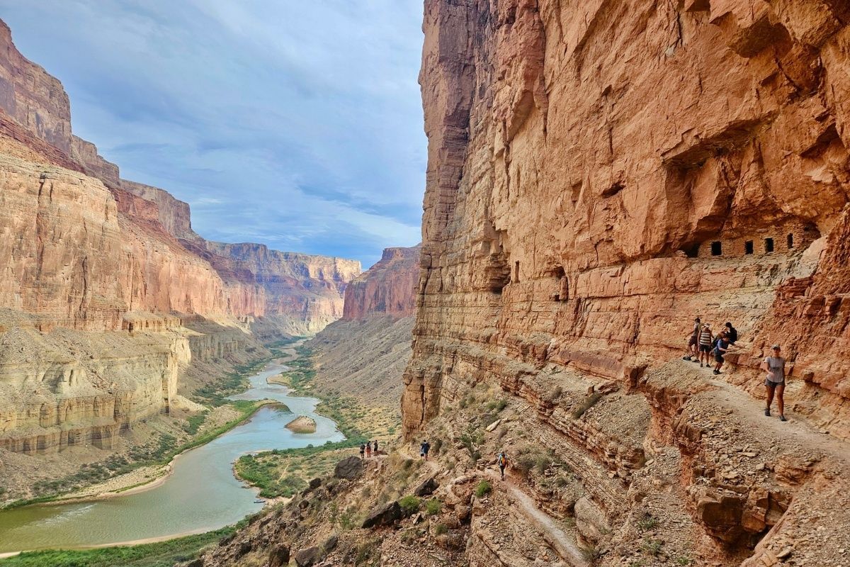 A group of people standing on top of a cliff overlooking a river.