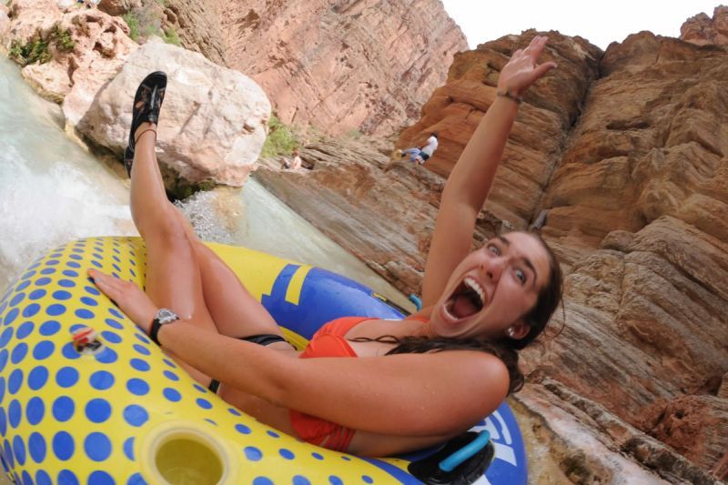 A woman in a bikini is laying on a raft with the letter t on it
