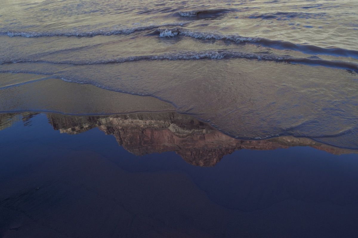 A reflection of a mountain in a body of water.