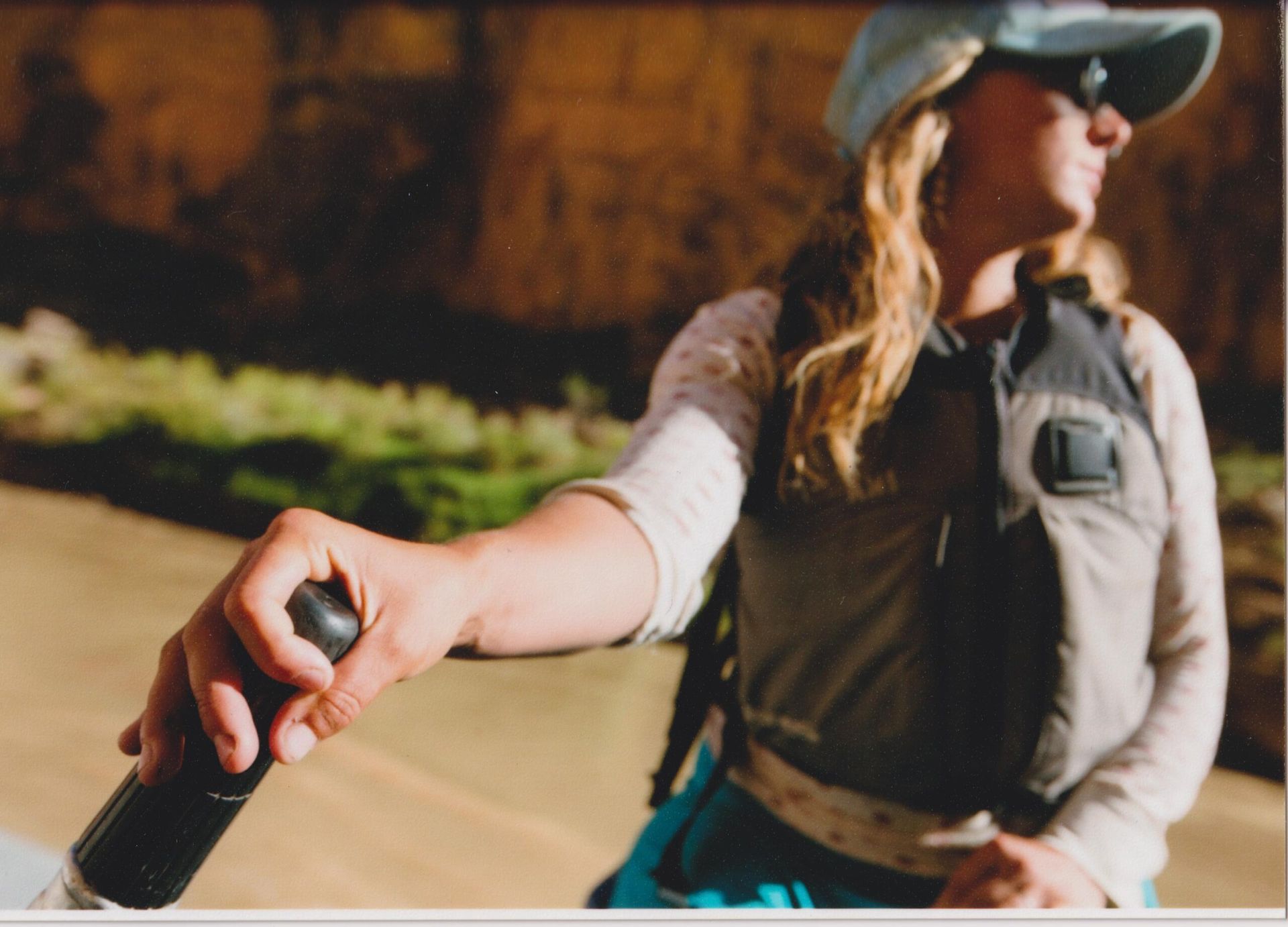 A woman wearing a hat and sunglasses is holding a black object