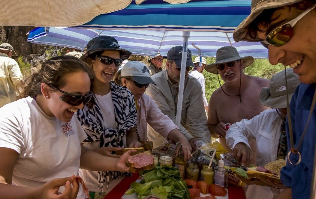 A group of people are standing around a table eating food.