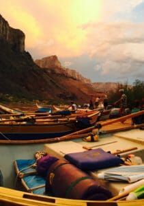 A group of boats are sitting on the shore of a river.