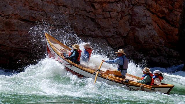 A group of people are rowing a boat down a river