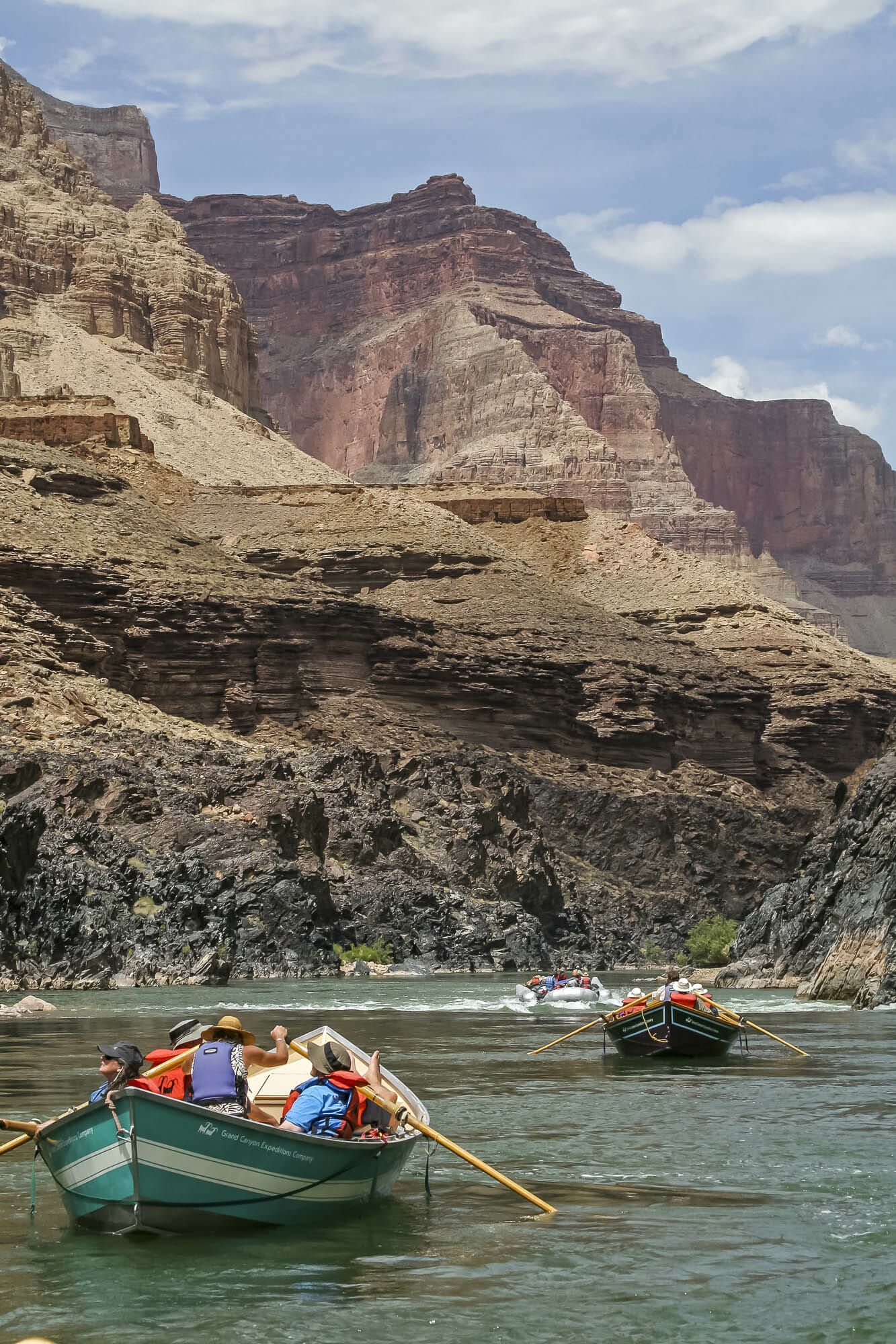 A group of people in a boat on a river with mountains in the background