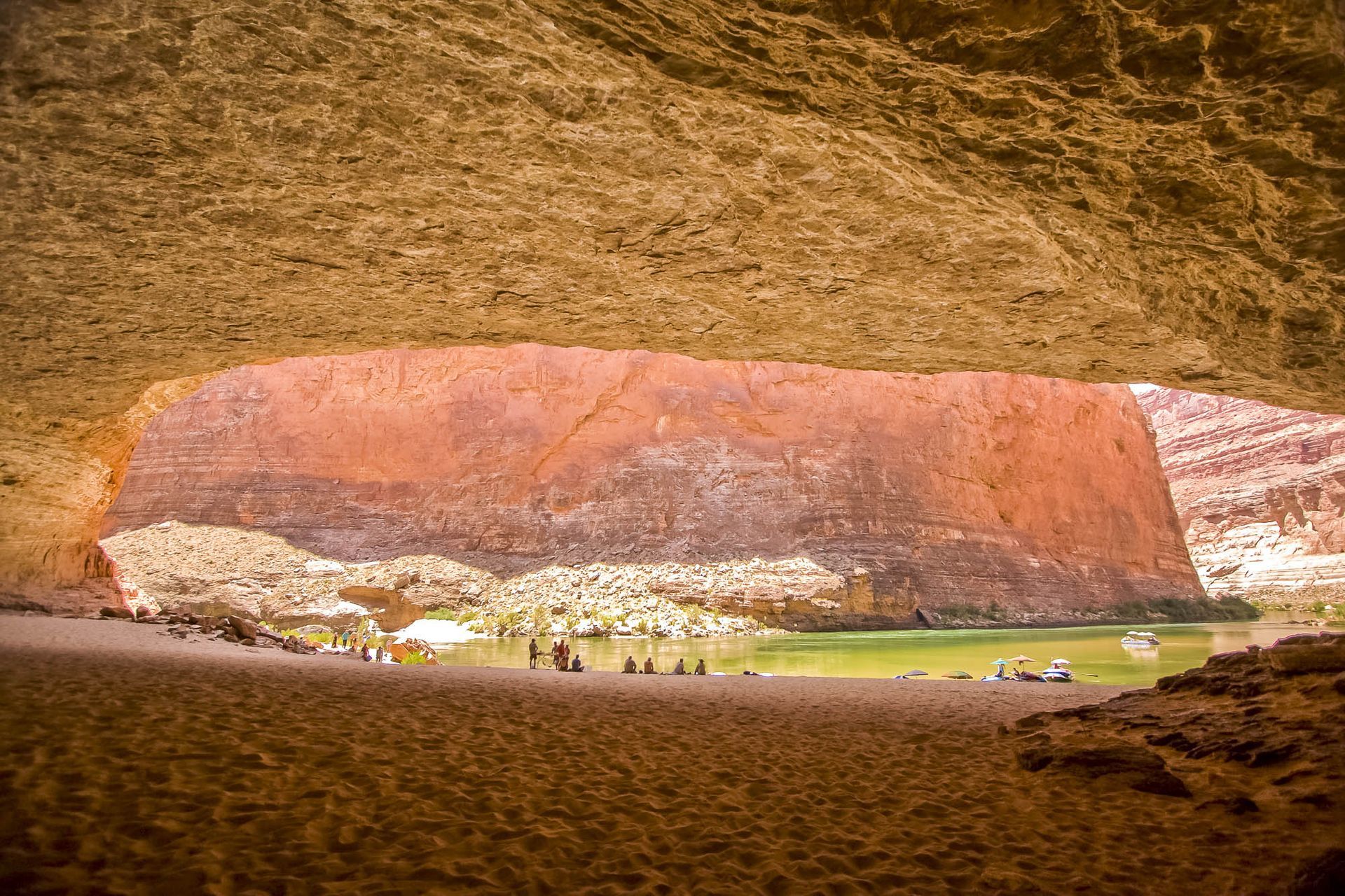 A group of people are standing in front of a large rock formation.