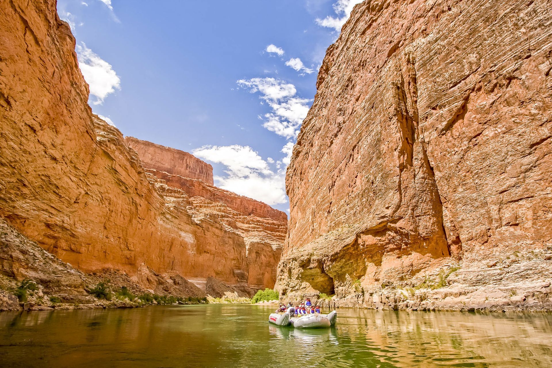 A group of people are rafting down a river in a canyon.