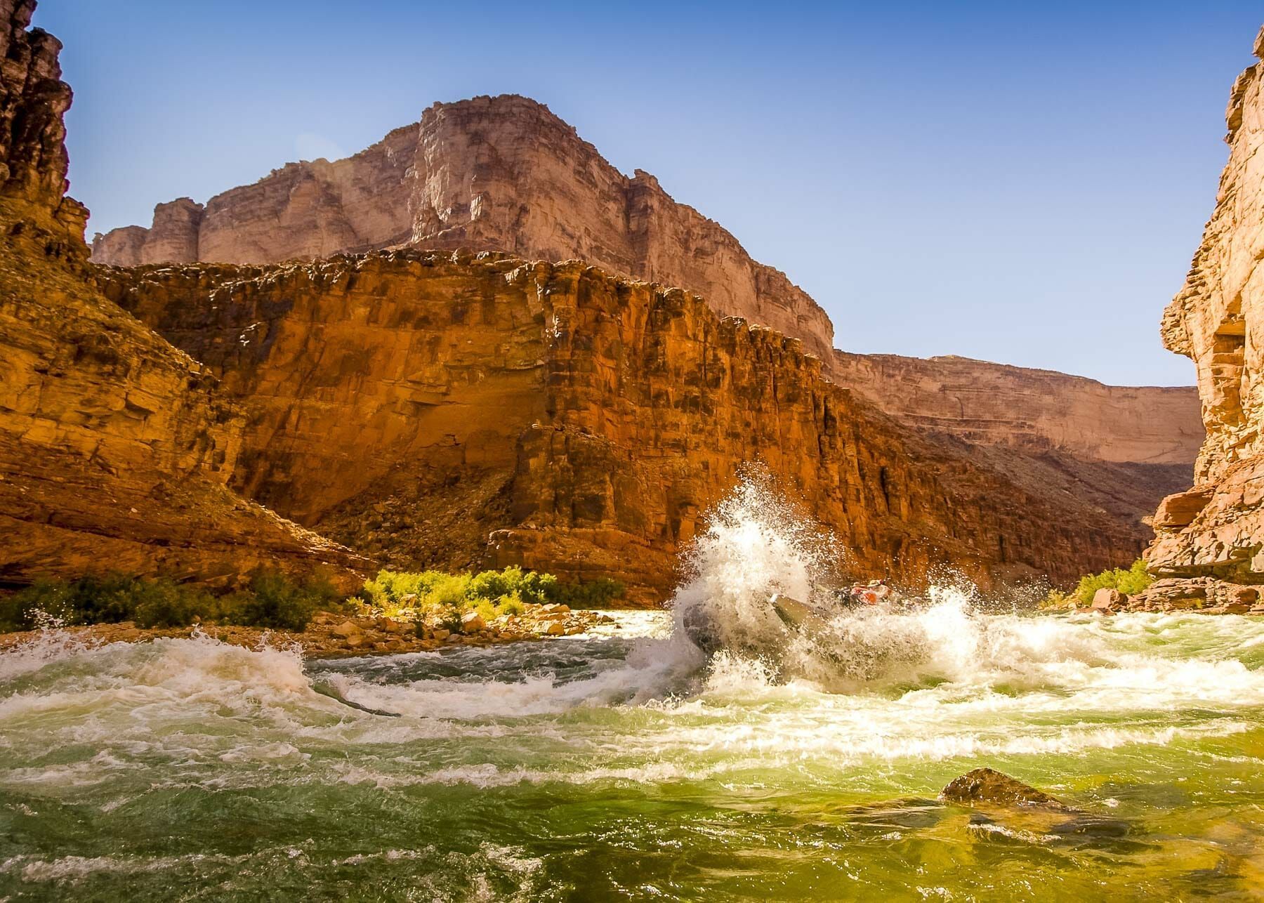 A river flowing through a canyon with mountains in the background.