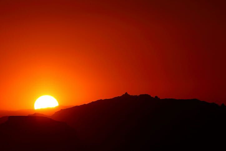The sun is setting over a mountain in the distance.