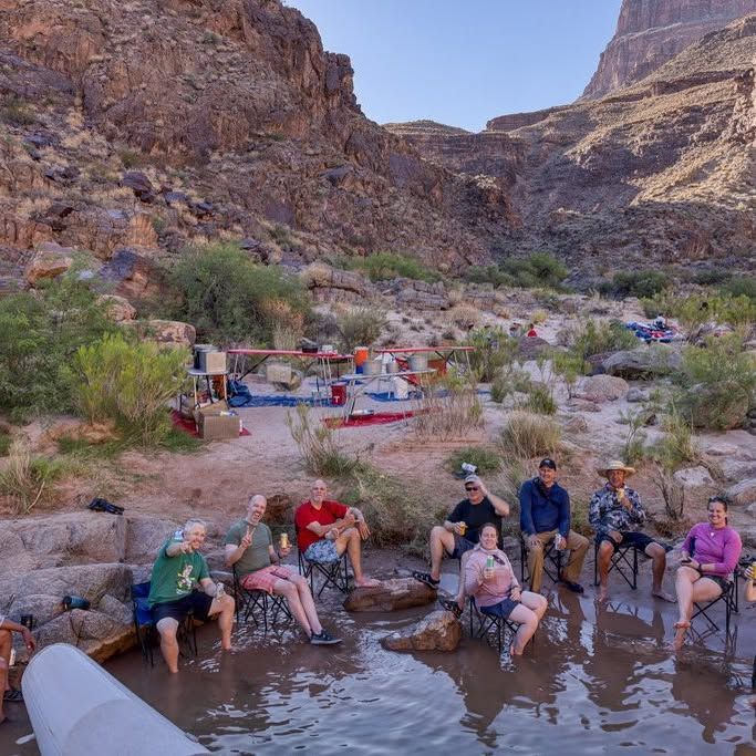 A group of people are sitting on rocks in the water.