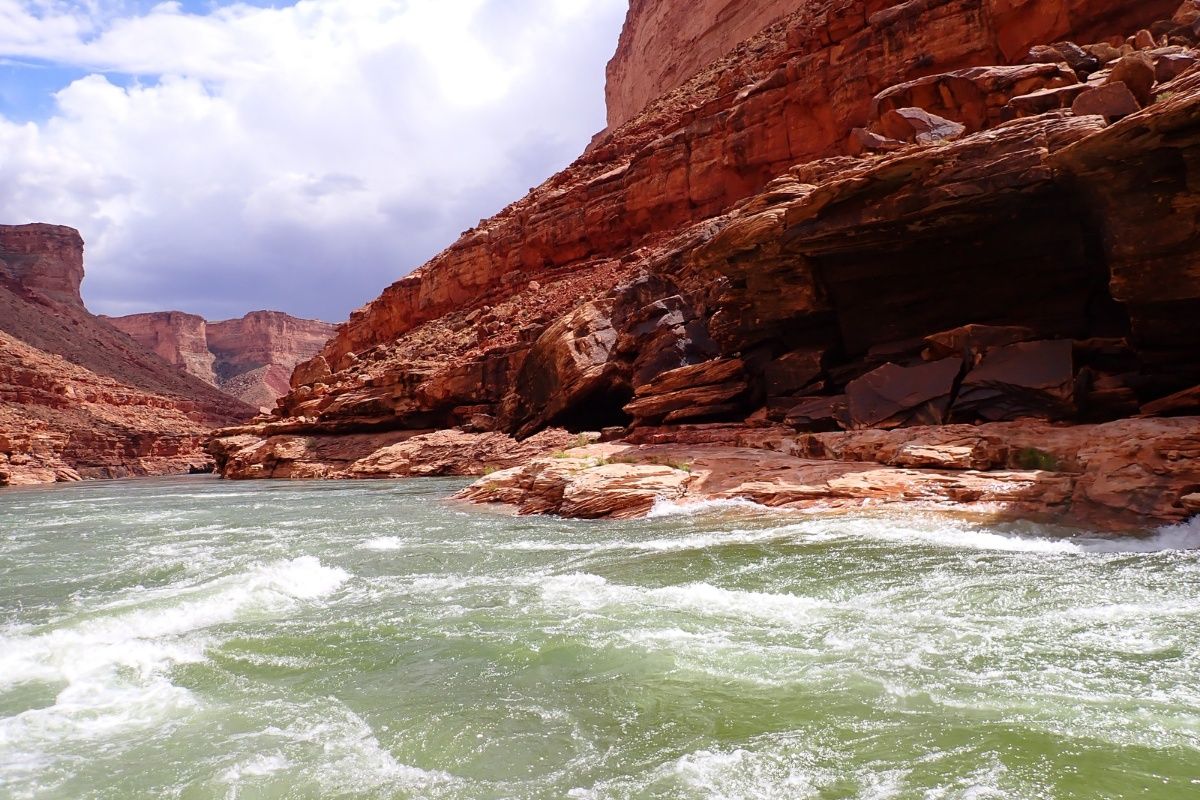 A river flowing through a canyon with a cave in the background