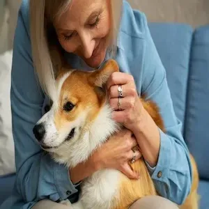 Woman hugging a small tan-and-white dog on a blue couch