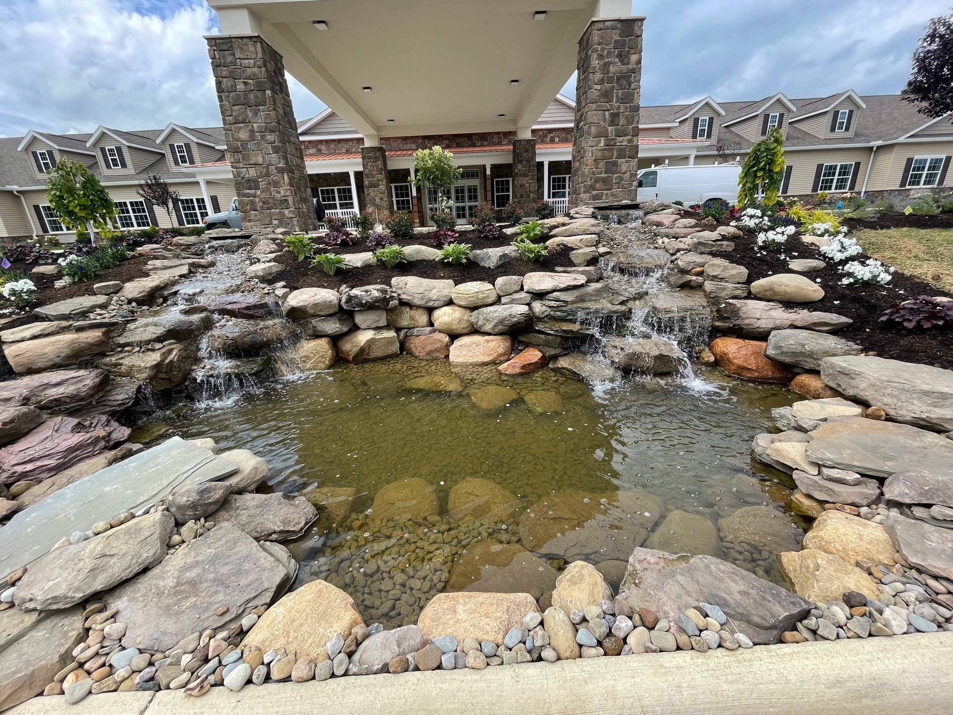 A waterfall is surrounded by rocks in front of a building.
