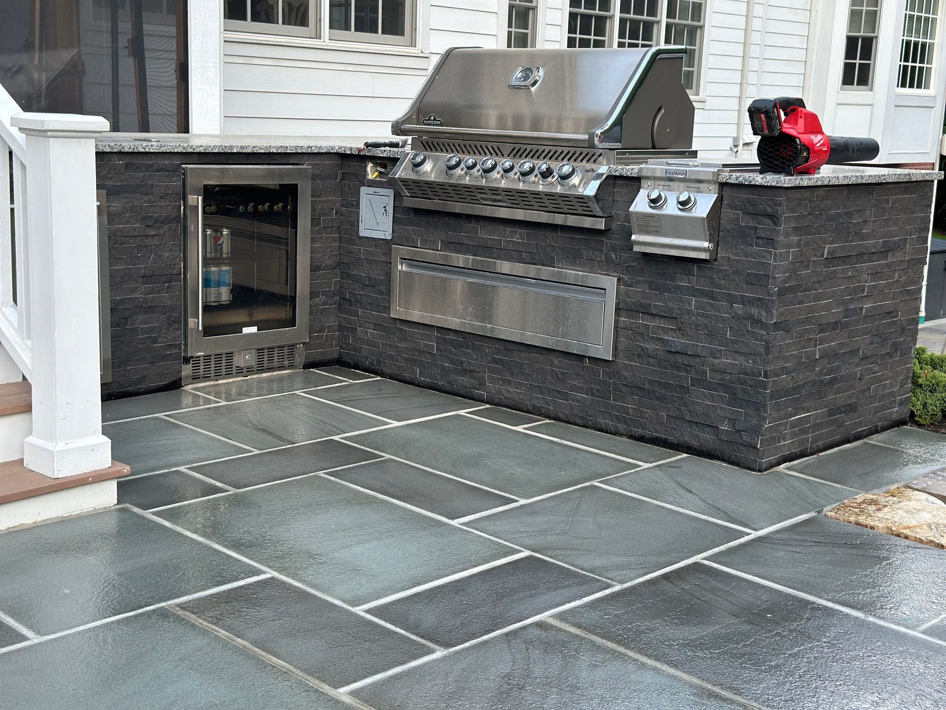 An outdoor kitchen with a grill and a refrigerator