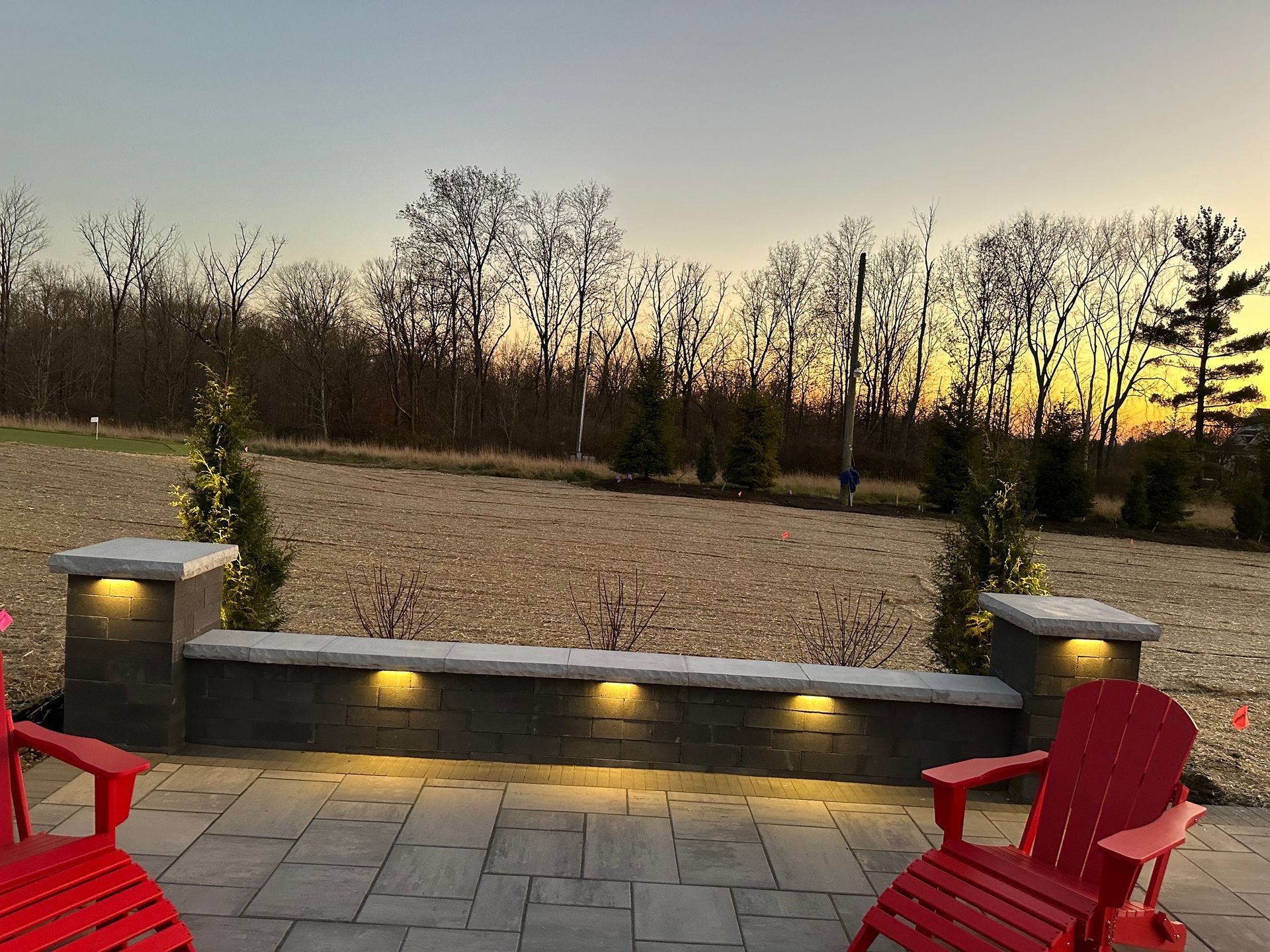 Two red chairs are sitting on a patio next to a wall.